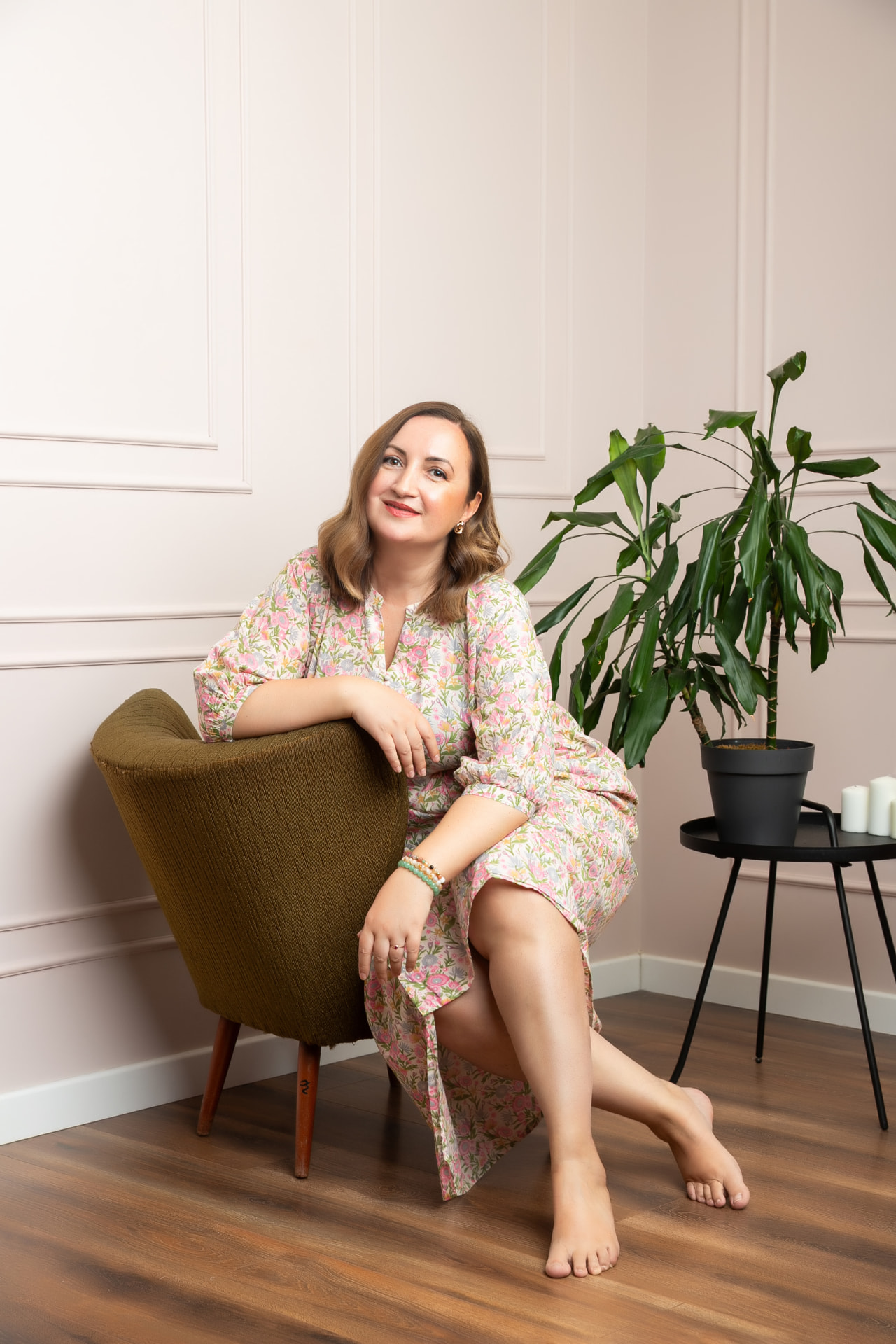 Ioana, mindset coach, sitting in an olive armchair in a calm room with soft pink walls